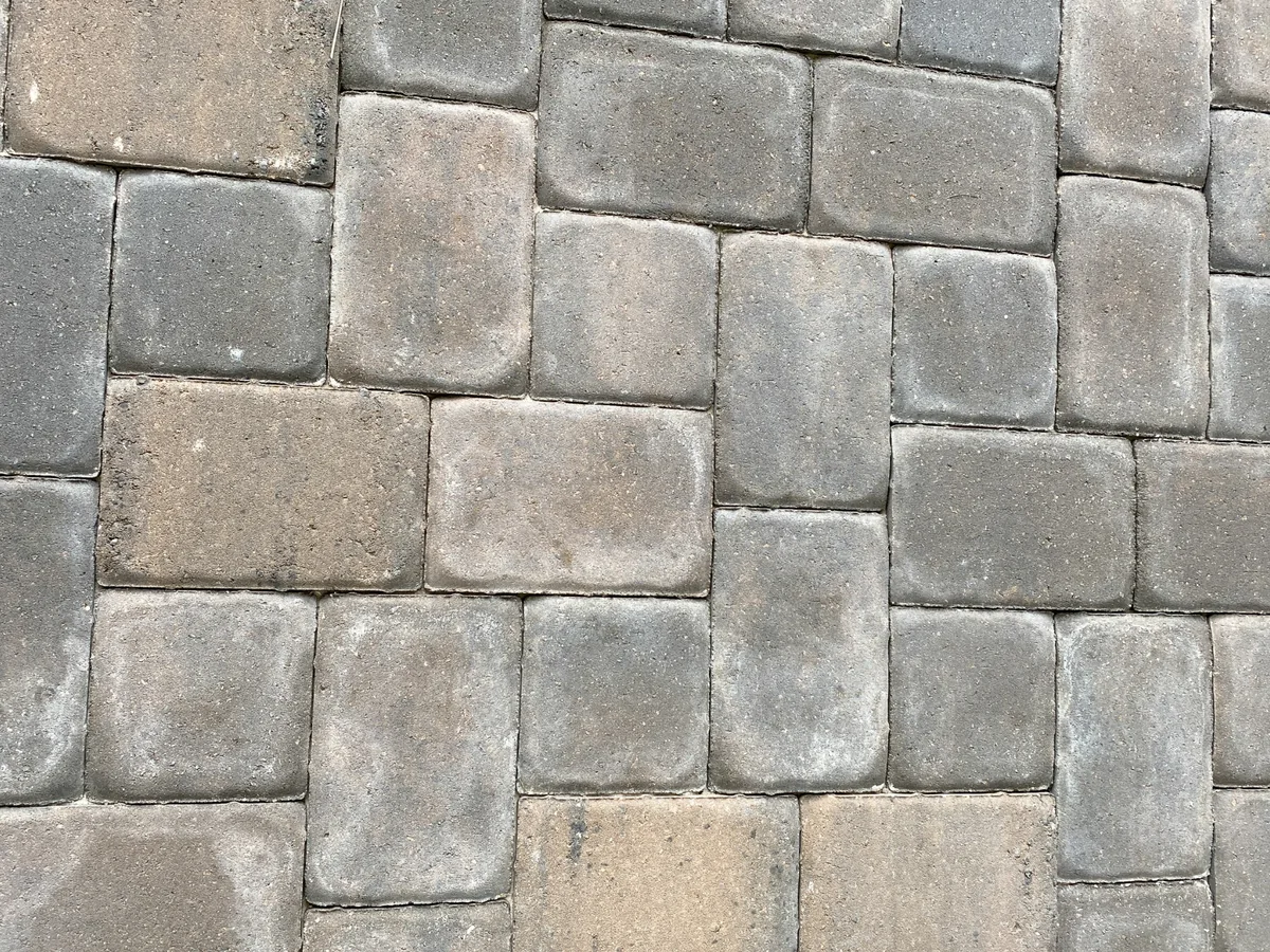 Close view of tumbled grey concrete pavers in a random three piece pattern